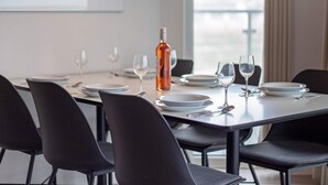 A dining area with a table set for four, chairs, and a bottle of wine.