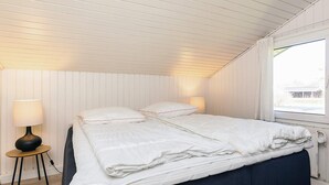 Ein Schlafzimmer mit Bett, Nachttischlampen, einem Fenster und einer Heizung.