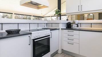 A modern kitchen with white cabinets, a black stove, and a large window.