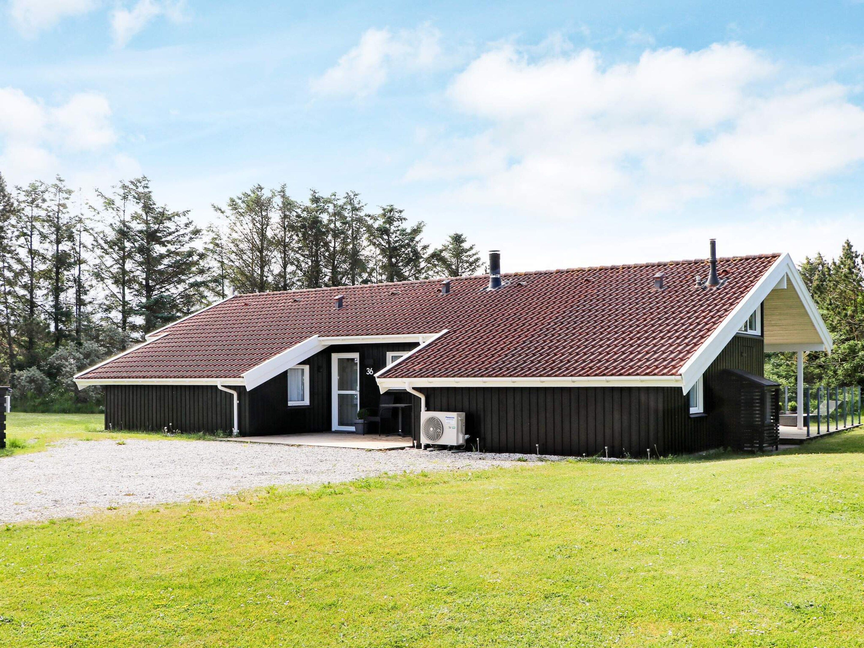 A two-story building with a red-tiled roof, a covered porch, and a gravel driveway.