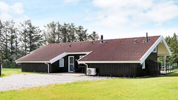 A two-story building with a red-tiled roof, a covered porch, and a gravel driveway.