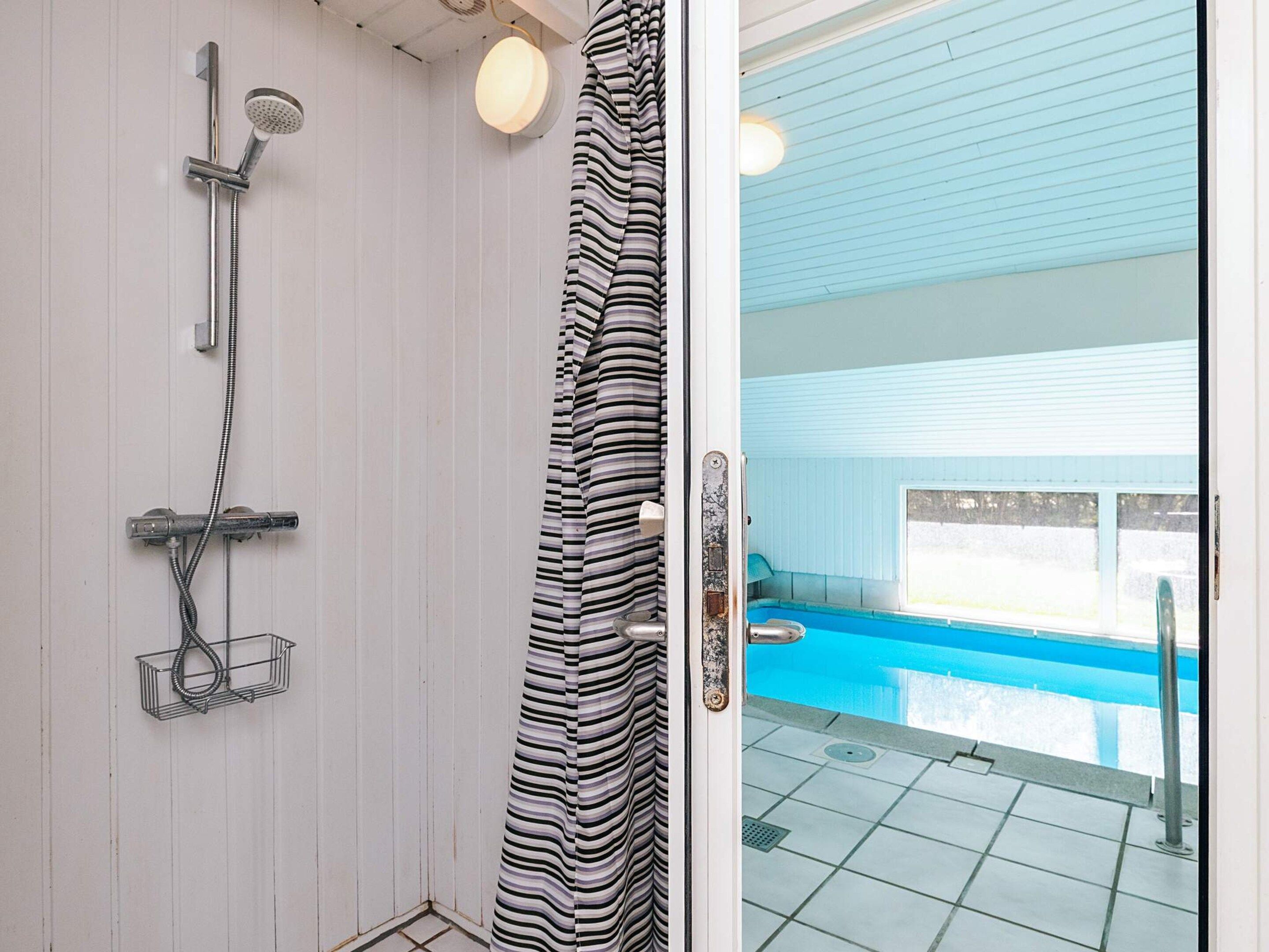 Baño con ducha, toallero y vista a una piscina exterior.