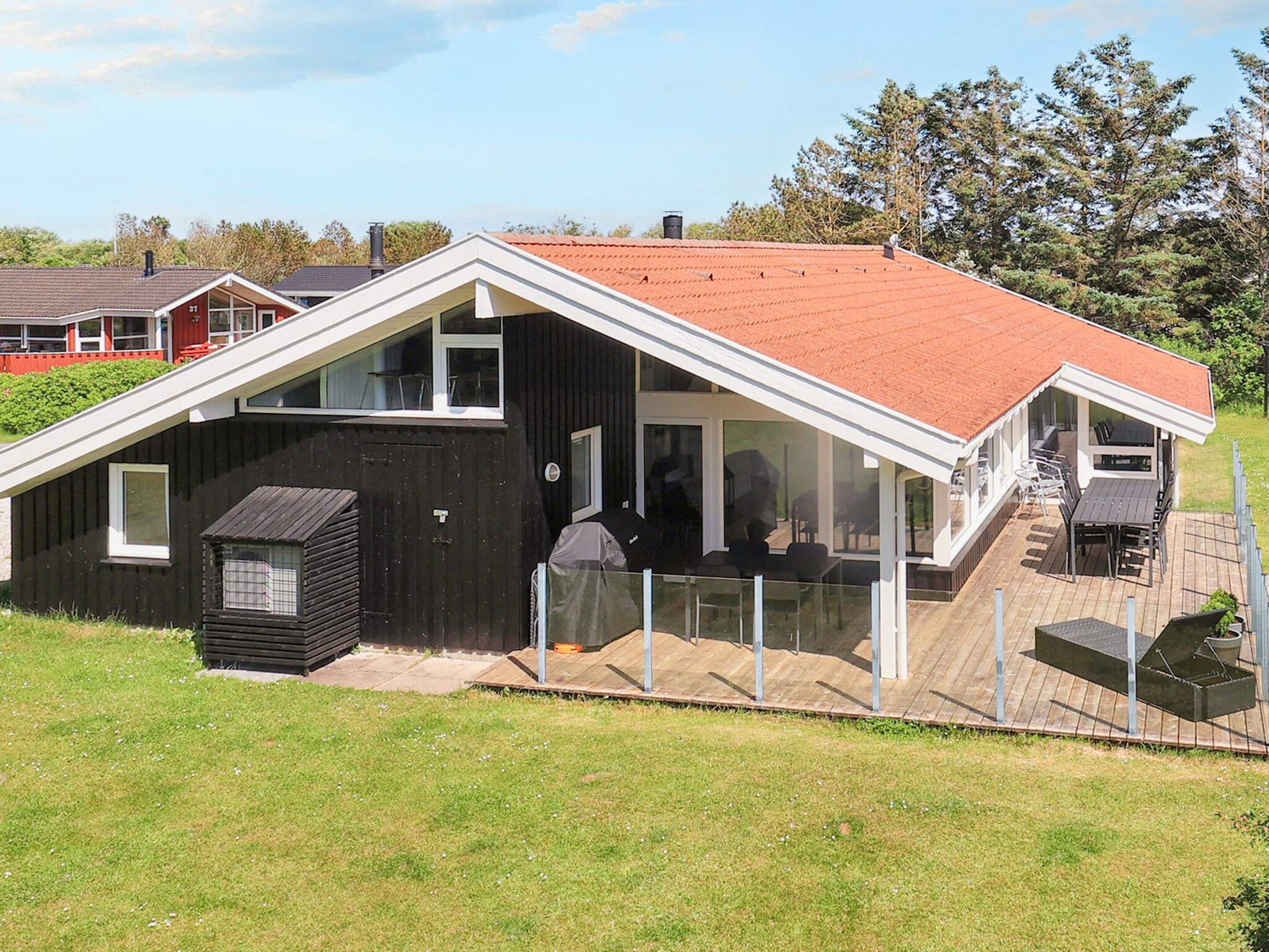 Ett modernt hus med ett sluttande tak, en täckt uteplats och en inhägnad trädgård.