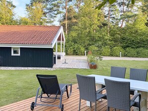 A deck with a table and chairs, a small shed, and a well-maintained lawn. - 4 Person Holiday Home in Oksbol (Oksbol)