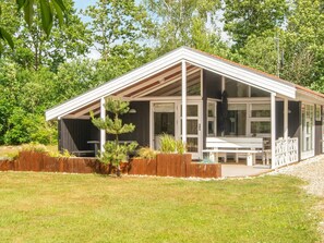 A modern house with a covered porch, a wooden fence, and a small tree. - 4 Person Holiday Home in Oksbol (Oksbol)