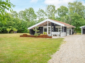 A modern house with a covered porch, a gravel driveway, and a grassy yard. - 4 Person Holiday Home in Oksbol (Oksbol)