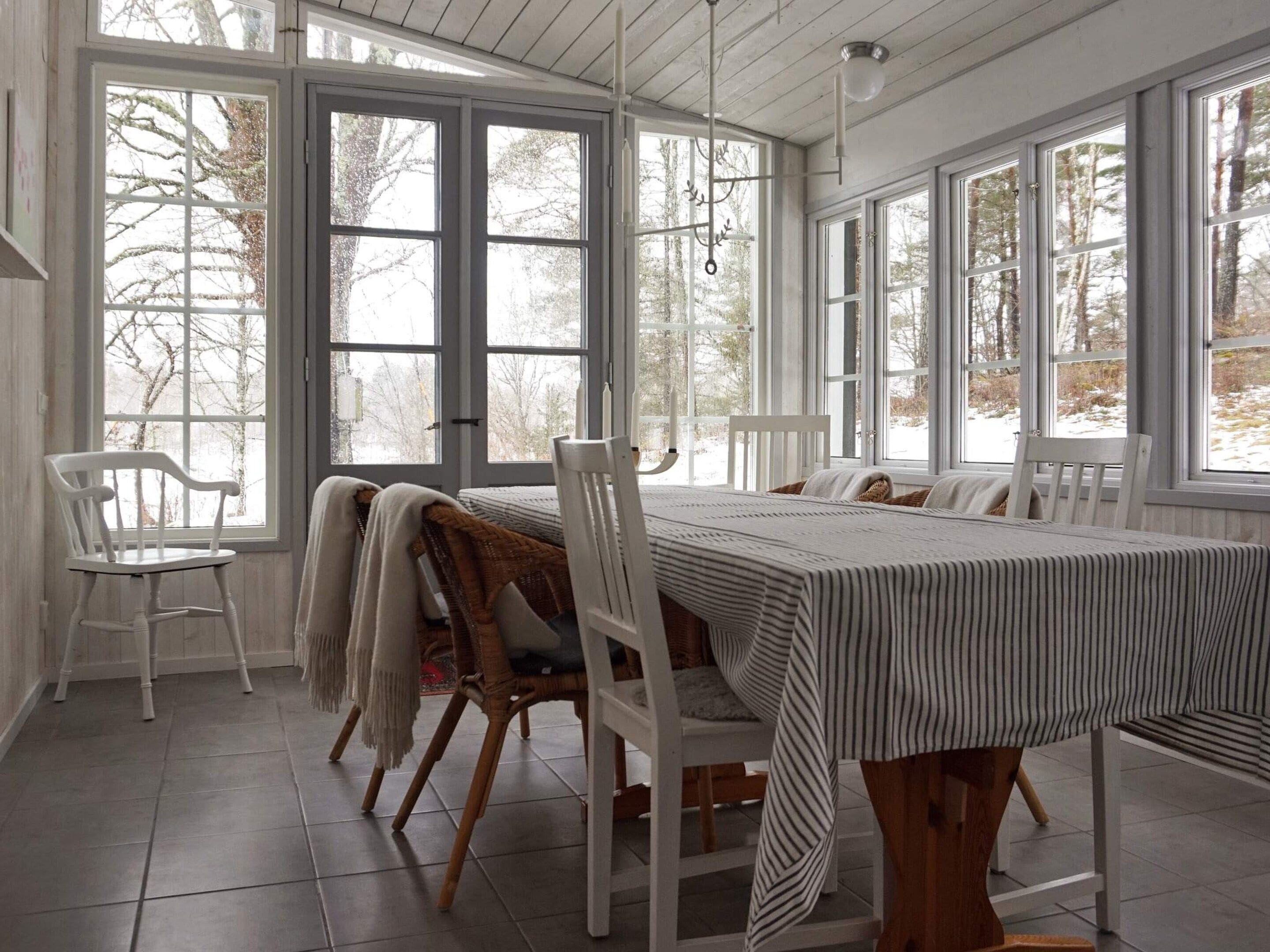 Un comedor con una mesa grande, sillas y ventanas amplias.