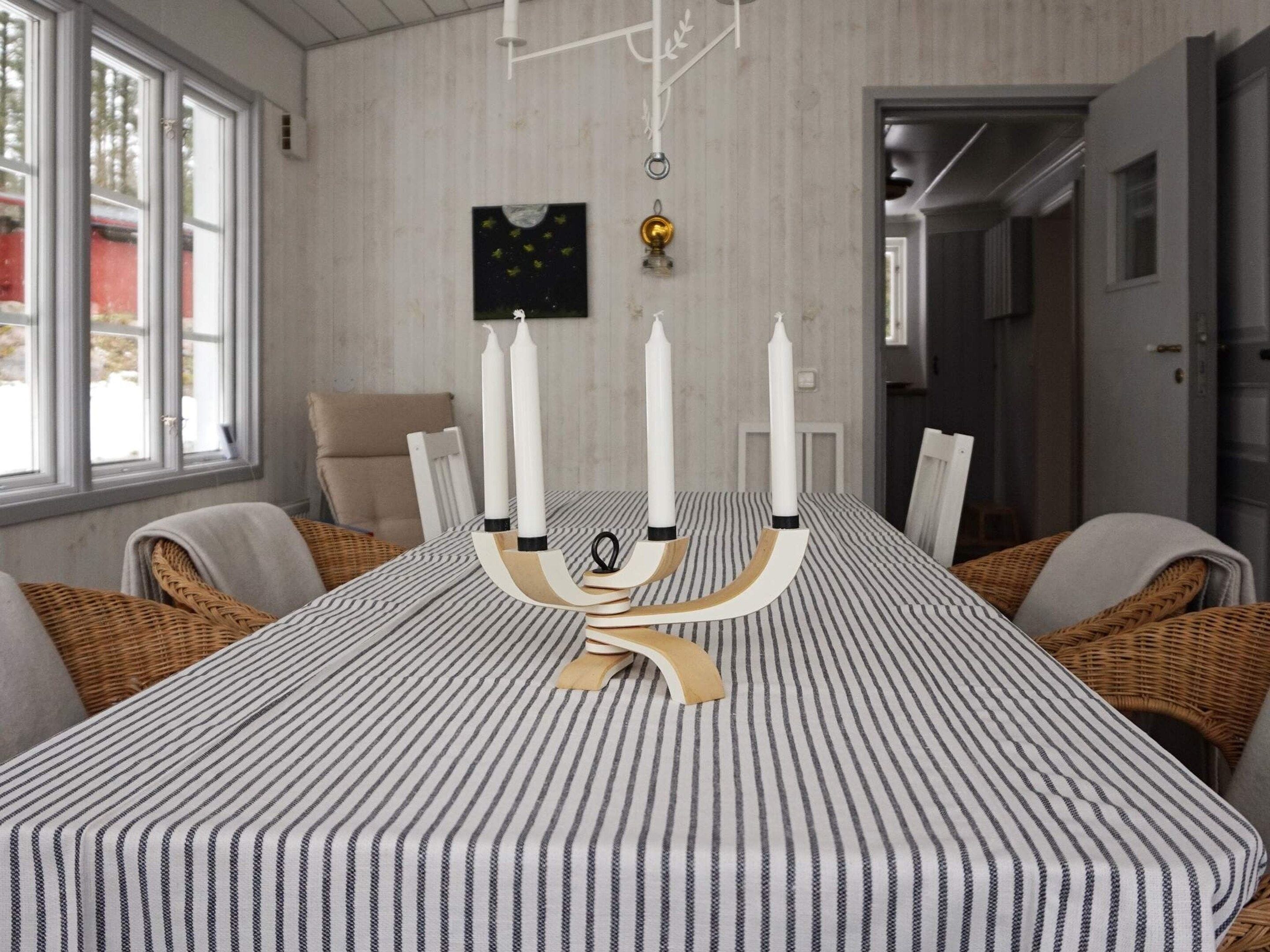 A dining area with a striped tablecloth, white candles, and wicker chairs.