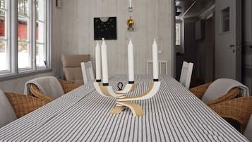 A dining area with a striped tablecloth, white candles, and wicker chairs.