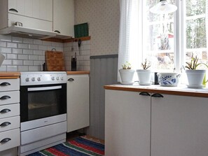 A kitchen with white cabinets, a stove, and a window with potted plants. - 6 Person Holiday Home in Atvidaberg-by Traum (Atvidaberg)