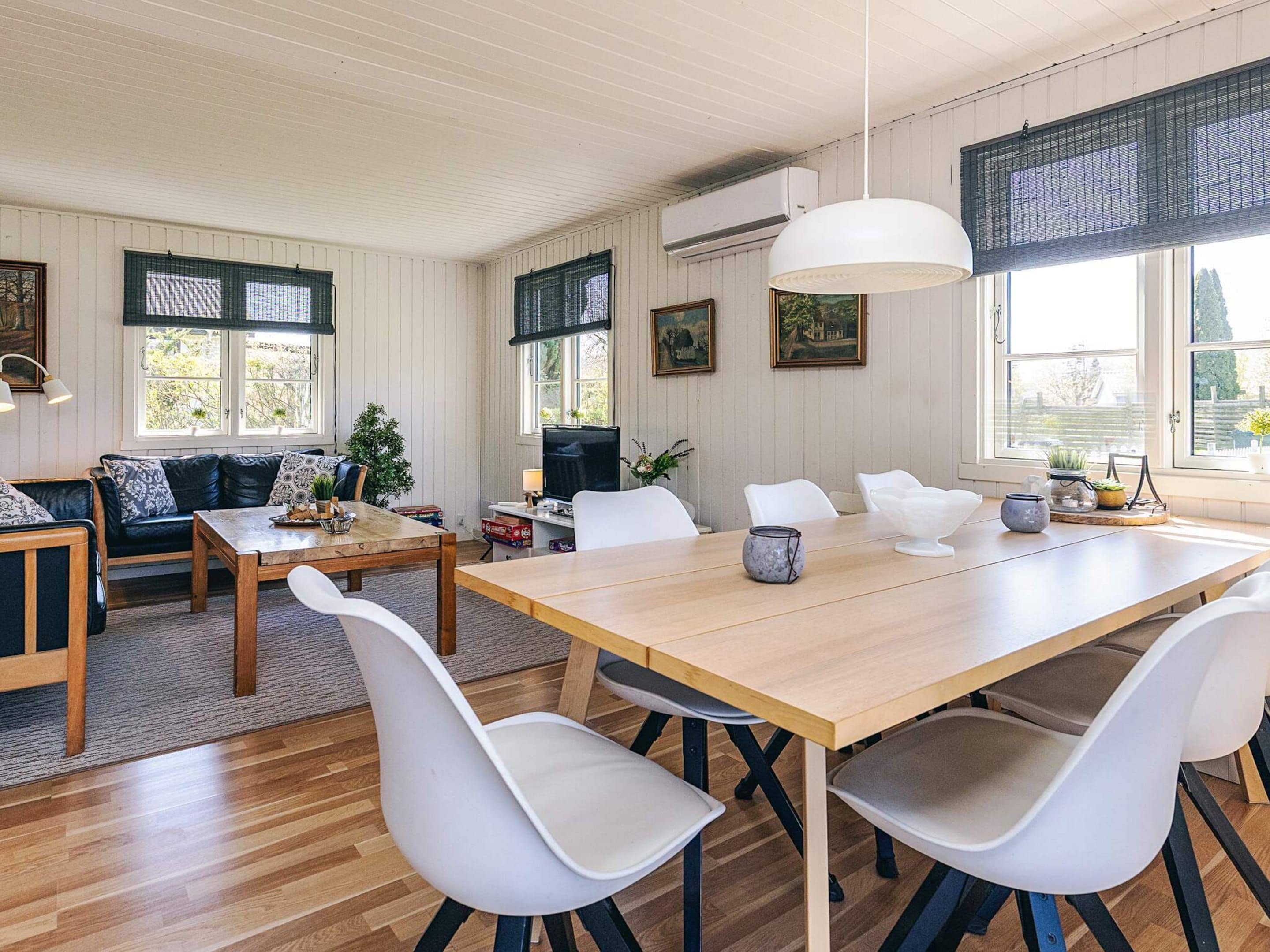 A dining area with a wooden table, white chairs, and a hanging light fixture.