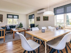 Un comedor con una mesa de madera, sillas blancas y una lámpara colgante.