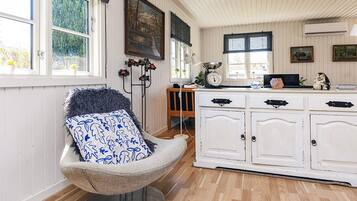 A cozy room with a chair, a white cabinet, and a window with a view of trees.