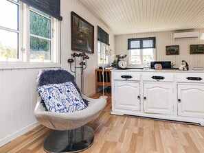 A cozy room with a chair, a white cabinet, and a window with a view of trees. - 4 Star Holiday Home in Kirke Hyllinge (Kirke Hyllinge)