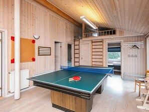 A ping pong table in a room with wooden walls and a loft area.