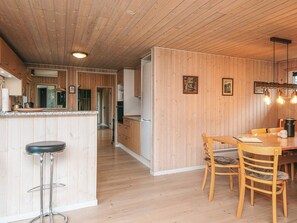 Un intérieur en bois comprenant une cuisine, un coin repas et des tabourets de bar.
