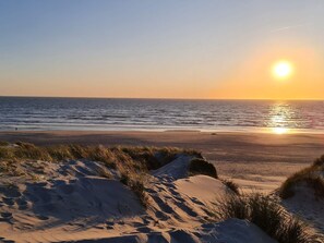 Una playa con dunas de arena y el océano.
