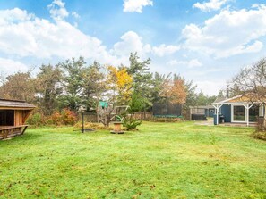 A backyard with a trampoline, a wooden playhouse, and a covered seating area. - 10 Person Holiday Home in Oksbol (Oksbol)