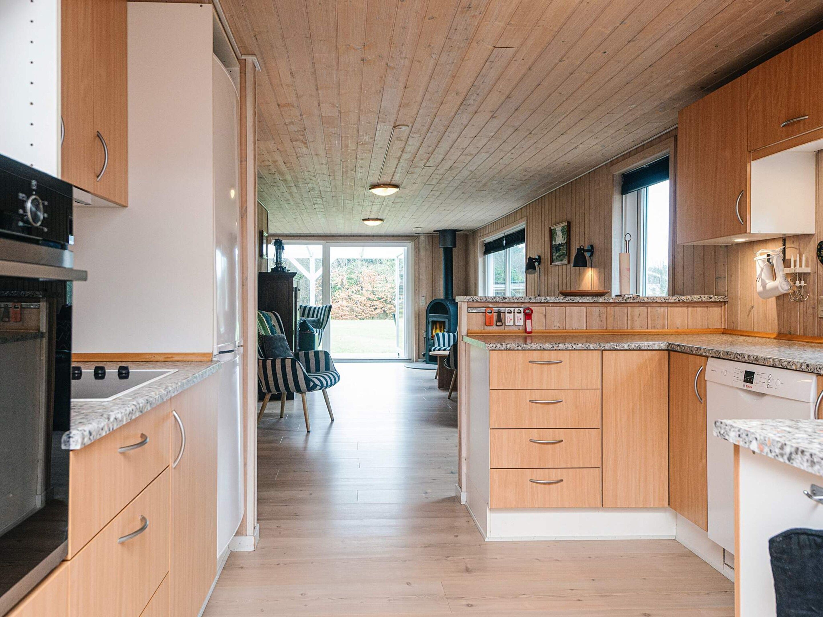 Una cocina moderna con armarios de madera, horno empotrado y una isla grande con lavavajillas.