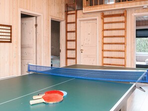 Una mesa de ping pong con dos paletas en una habitación con paredes y puertas de madera.