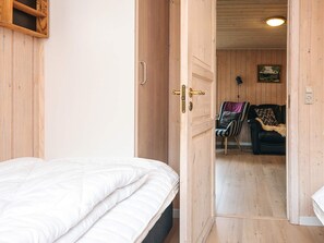 Una habitación con una cama, una puerta de madera y vistas a otra habitación con un sillón y un sofá.