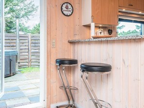 Un coin cuisine avec des murs en bois, un plan de travail et deux tabourets de bar.