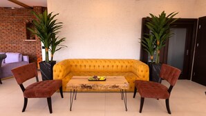 A yellow sofa with a wooden coffee table, two brown chairs, and two potted plants. - Grand Isbilir Hotel (Nevşehir)