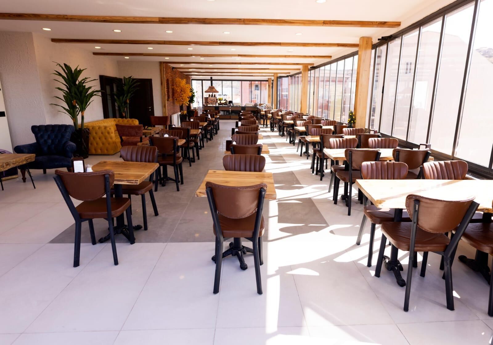 A spacious indoor dining area with multiple tables and chairs, large windows, and a modern interior design.