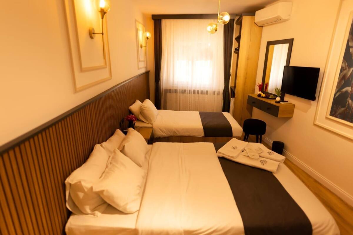 A hotel room with two beds, a desk, a chair, a TV, and a mirror.
