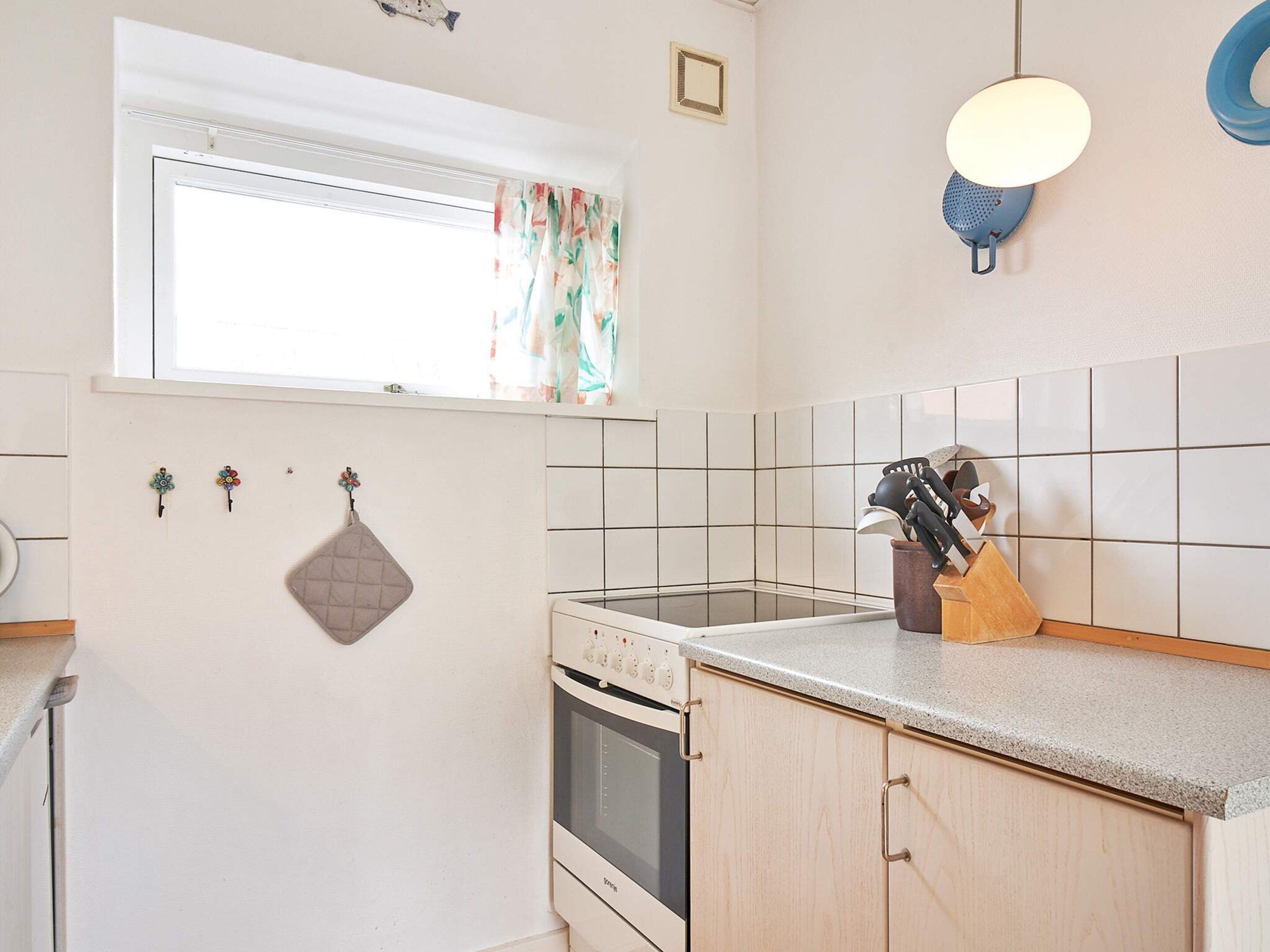 A kitchen with a window, a stove, and a countertop with kitchen utensils.