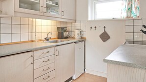 A kitchen with white cabinets, a coffee maker, and a window with curtains.