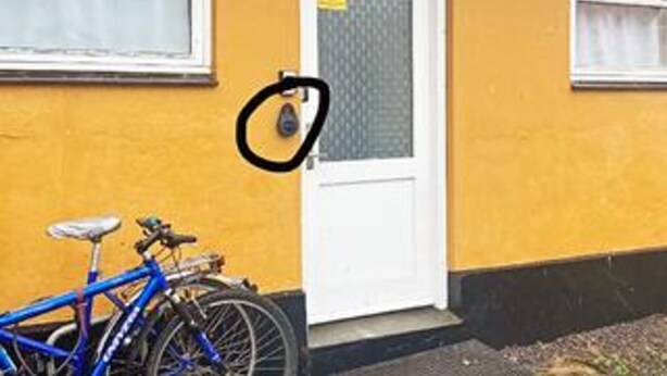 A bicycle parked next to a building with a white door and windows.