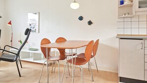 A modern kitchen with a round table and chairs, a pendant light, and a cabinet with dishes.