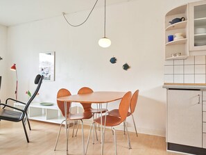 A modern kitchen with a round table and chairs, a pendant light, and a cabinet with dishes. - 2 Person Holiday Home in Aakirkeby (Akirkeby)