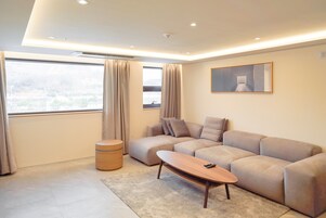 Una sala de estar moderna con un sofá modular, una mesa de centro de madera y un ventanal con cortinas.