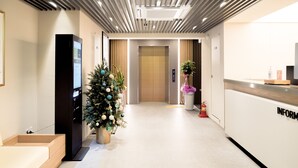 Un moderno vestíbulo de hotel con un mostrador de recepción, un árbol de Navidad, un extintor y un ascensor.