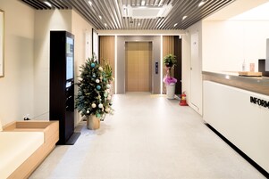Un moderno vestíbulo de hotel con un mostrador de recepción, un árbol de Navidad, un extintor y un ascensor.