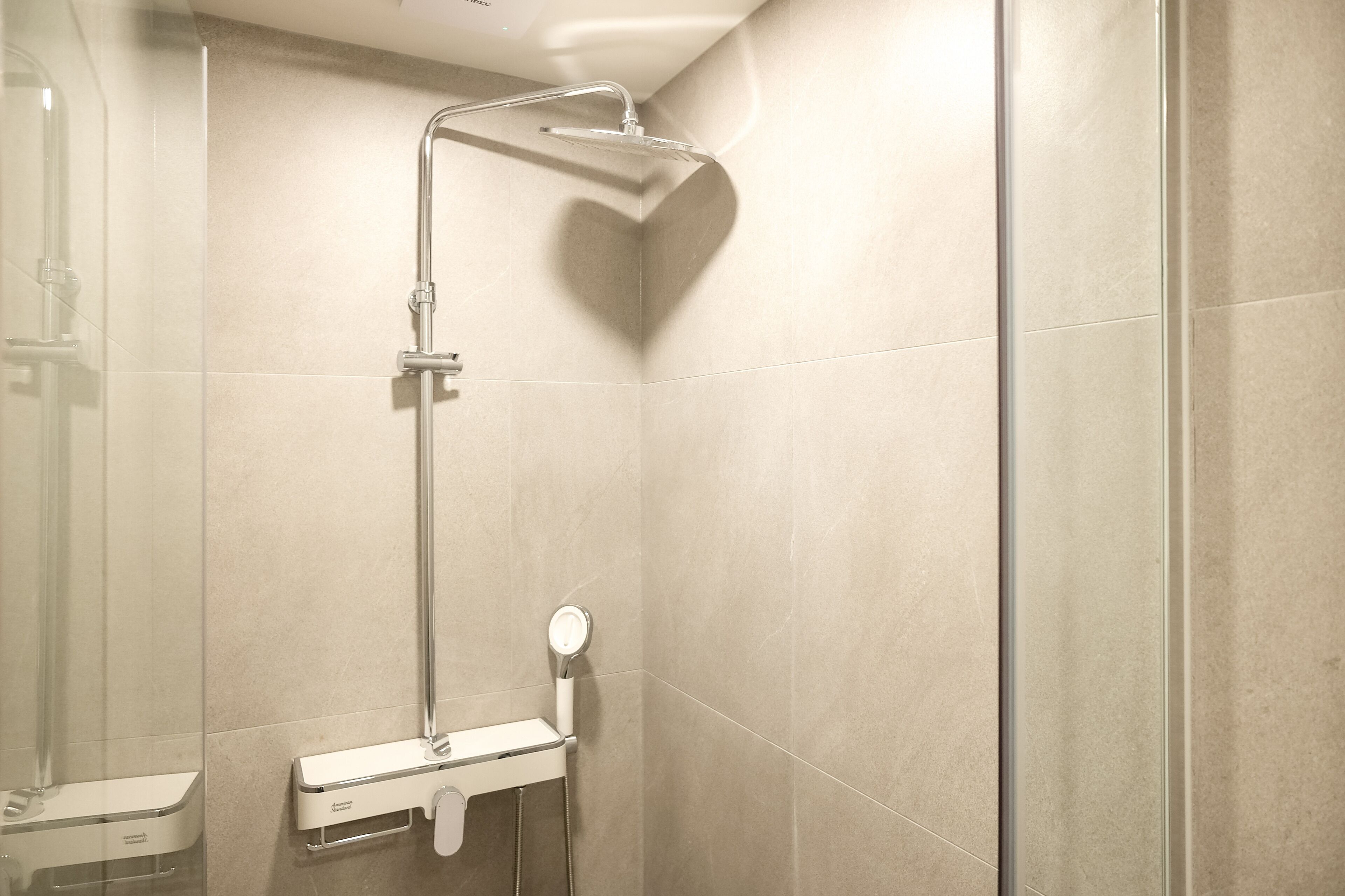 A modern shower with a handheld showerhead, a handheld mirror, and a wall-mounted faucet.