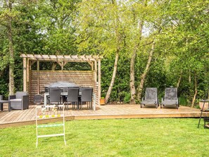 Une terrasse extérieure dotée d’une pergola en bois, d’une table ronde et de quatre chaises.