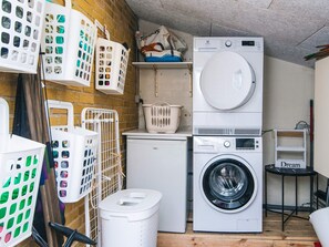 A laundry room with a front-loading washing machine, a dryer, and multiple laundry baskets.