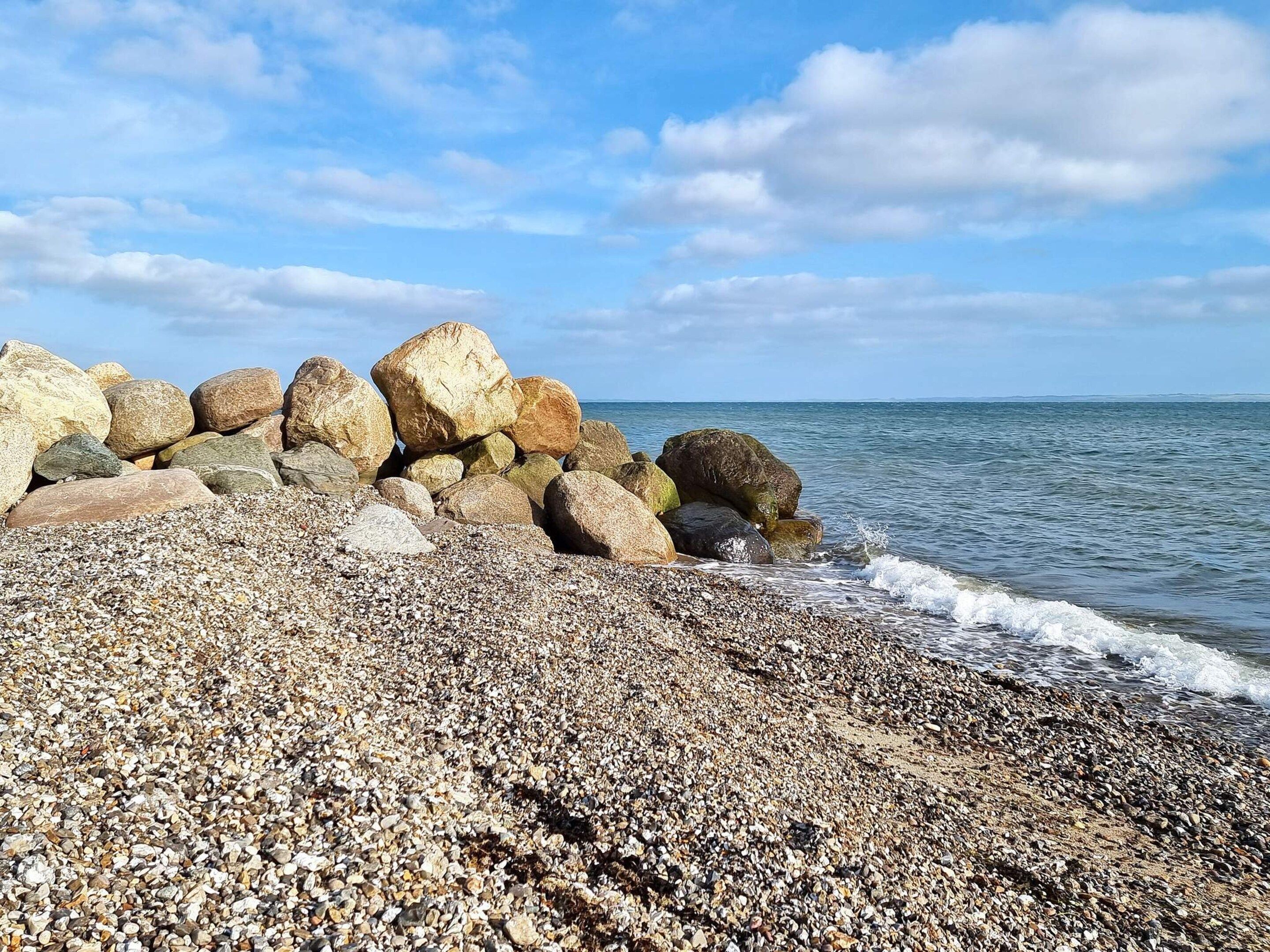 A pebbled beach with large rocks and the sea.