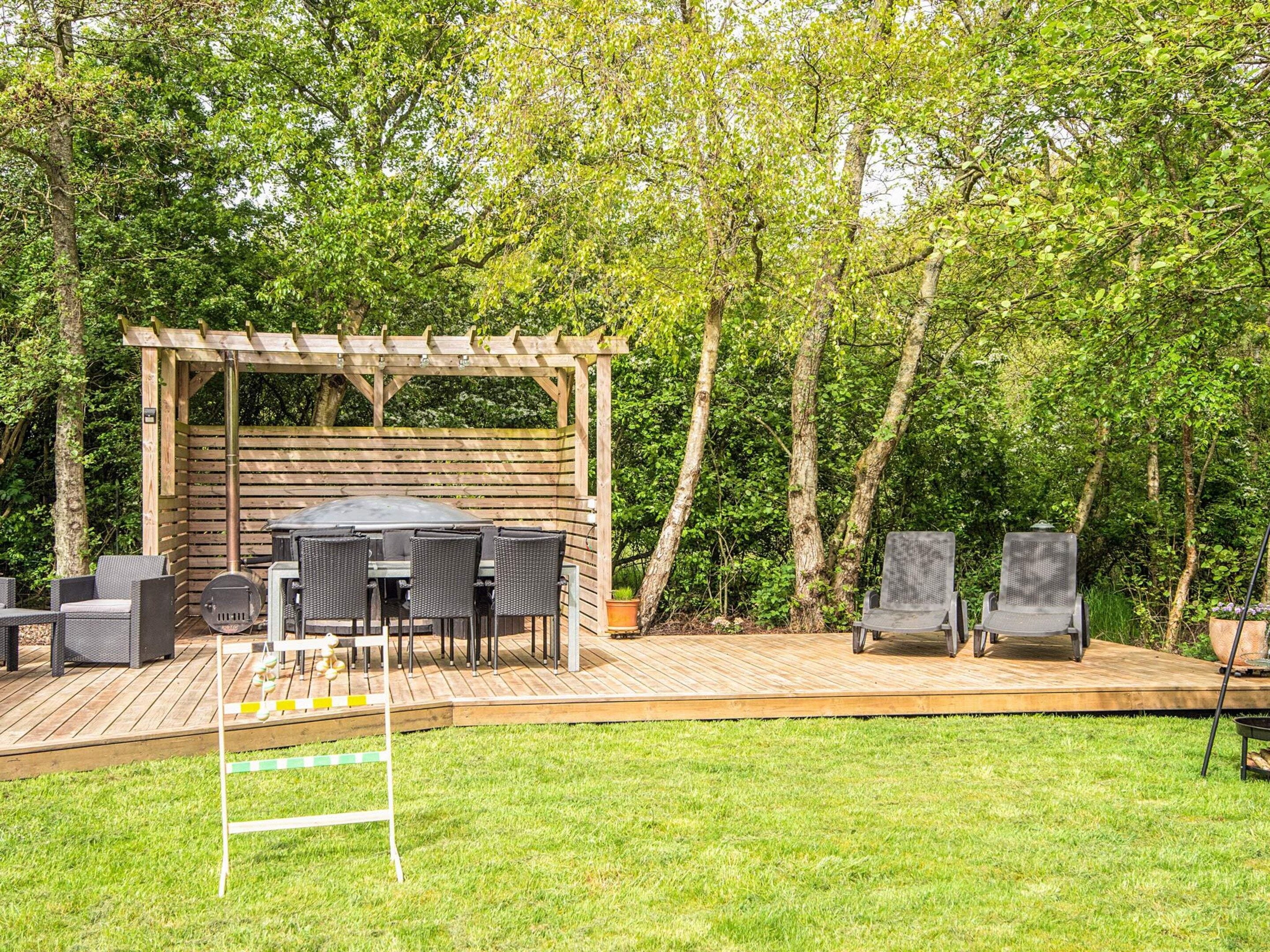 A wooden deck with a pergola, outdoor furniture, and a grill area.