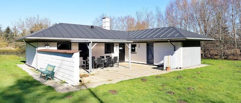 A single-story house with a covered patio area, a chimney, and a small shed.