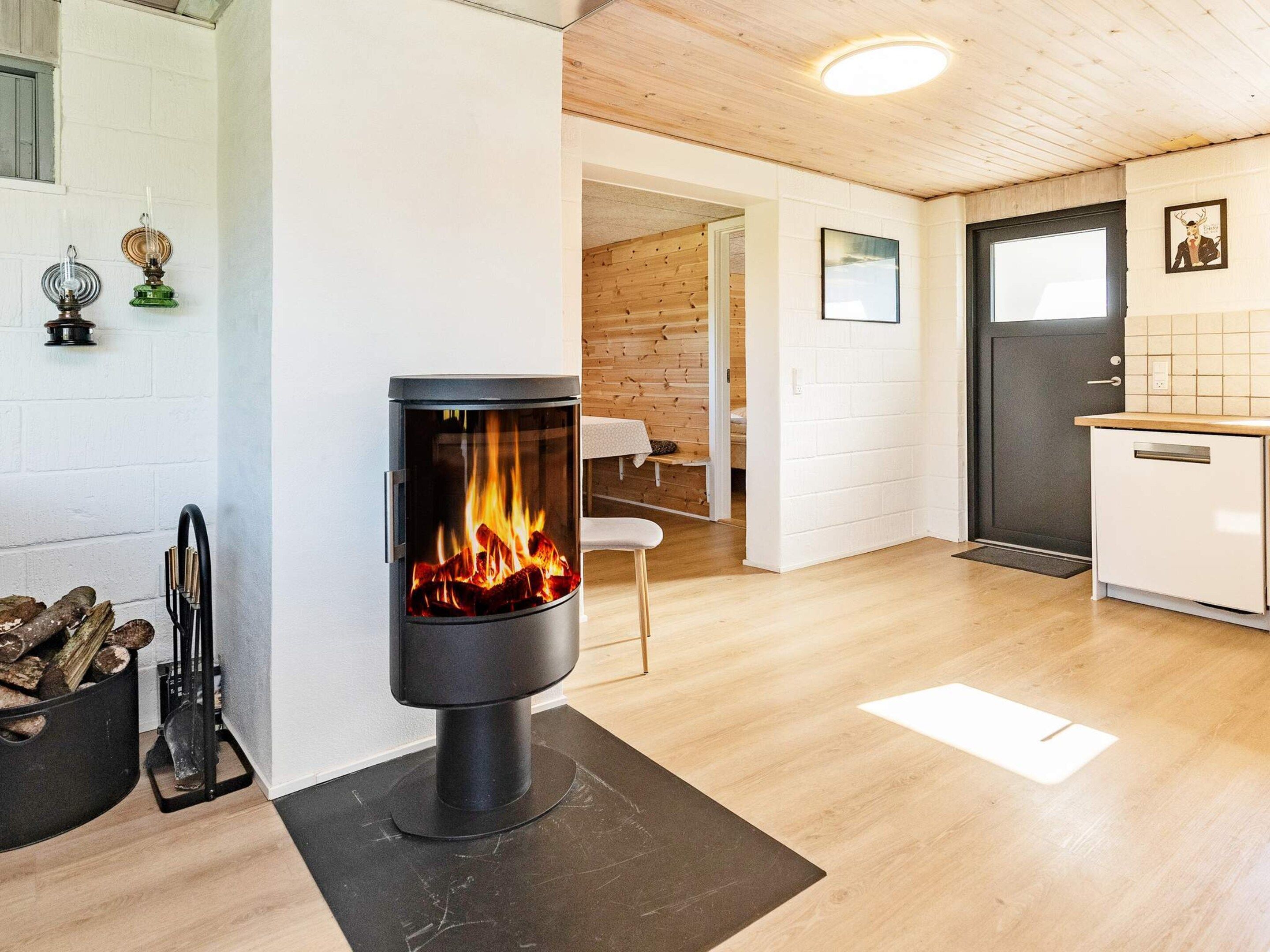 Um interior moderno com lareira a lenha, cozinha e uma porta que dá para outro quarto.