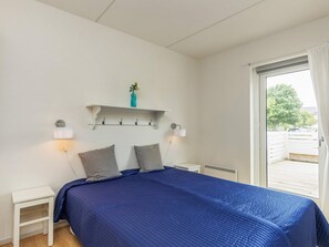 A bedroom with a bed, bedside tables, a shelf with a vase, and a window with a view. - 4 Person Holiday Home in Rudkobing (Rudkobing)