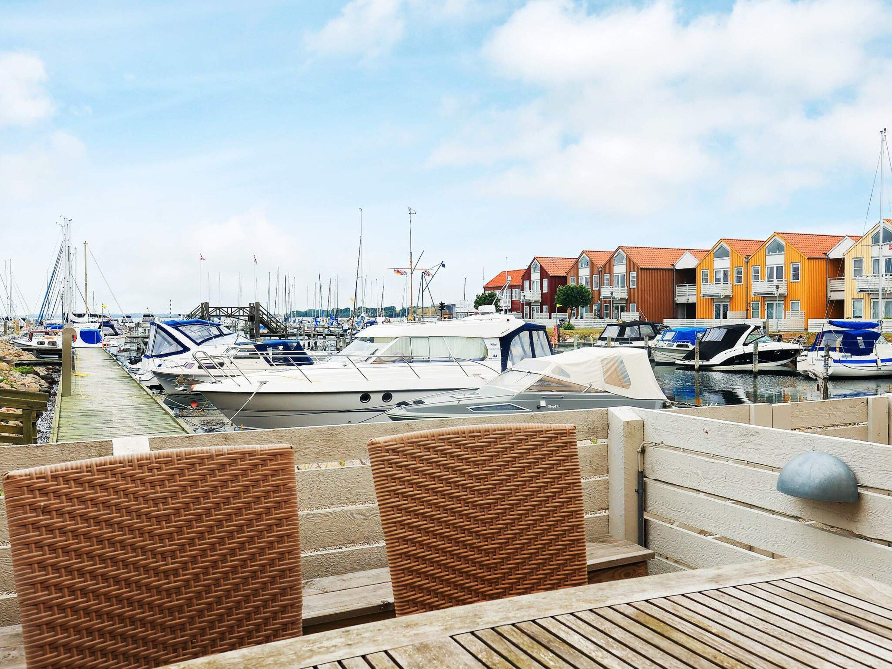 Un port esportiu amb embarcacions amarrades, un passeig de fusta i edificis de colors al fons.