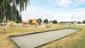 Ein Freizeitareal mit Schreibtischschachfeld, Picknicktischen und Spielgeräten.