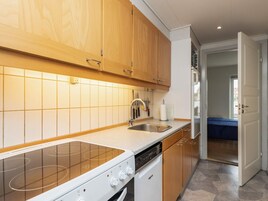 Una cocina moderna con armarios de madera, un lavamanos de acero inoxidable y un lavavajillas empotrado.