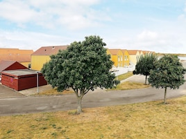 Zona residencial con casas, una calle pavimentada y dos árboles.