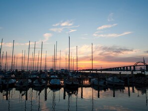 A marina with multiple boats docked at the pier during sunset.
